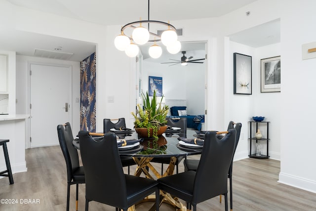 dining area with light hardwood / wood-style floors and ceiling fan with notable chandelier