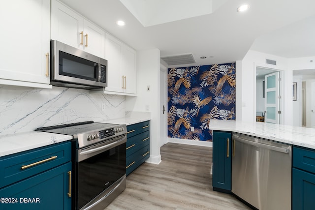 kitchen featuring stainless steel appliances, light stone counters, blue cabinetry, white cabinets, and light wood-type flooring