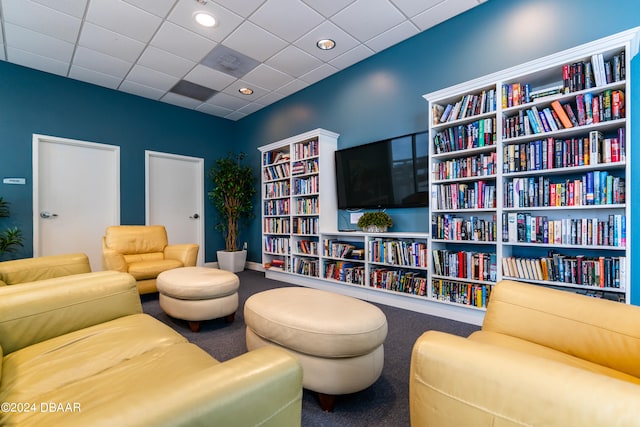 living area with a drop ceiling and carpet floors