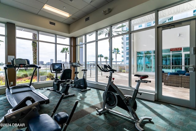 gym with a high ceiling, a paneled ceiling, and carpet floors