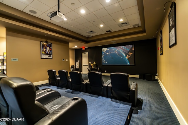 cinema room with a paneled ceiling, a tray ceiling, and carpet flooring