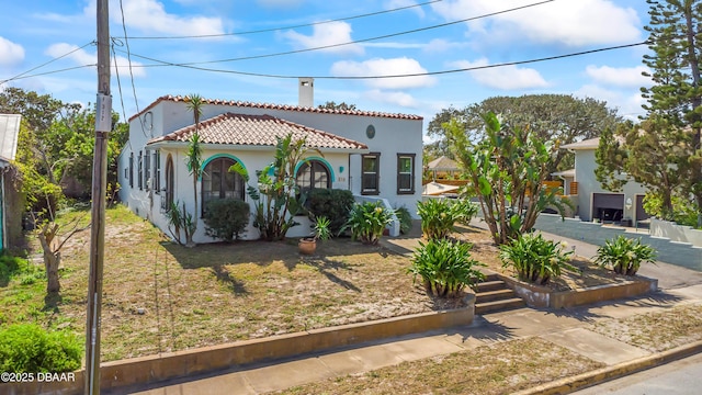 mediterranean / spanish-style house with a tiled roof, a front yard, and stucco siding
