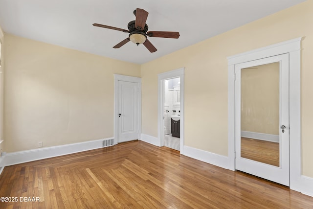 unfurnished room with ceiling fan, visible vents, baseboards, and wood finished floors