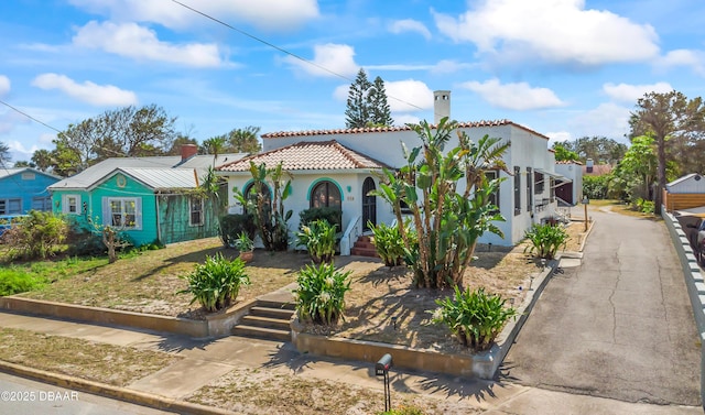 mediterranean / spanish-style home with a tiled roof, driveway, and stucco siding