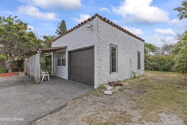 view of side of home with a tiled roof, aphalt driveway, and stucco siding