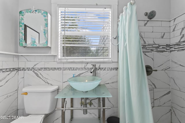 full bathroom with tile walls, a sink, a shower stall, and toilet