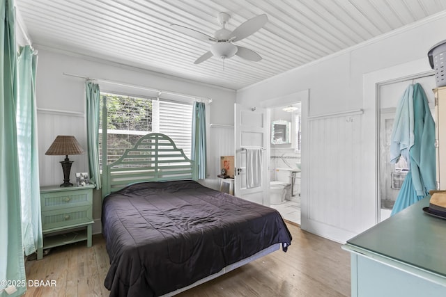bedroom with wainscoting, light wood-style flooring, and crown molding
