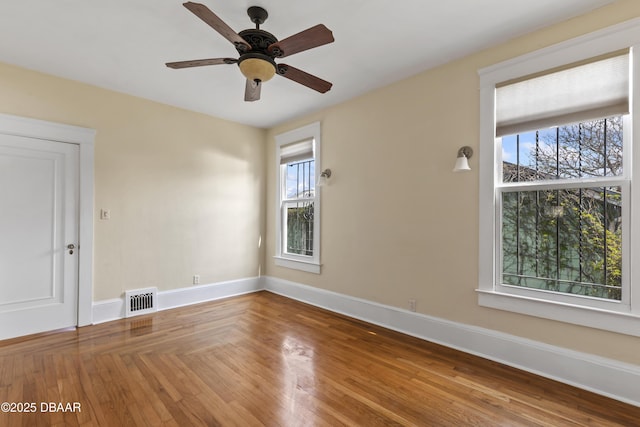 spare room with baseboards, visible vents, ceiling fan, and wood finished floors