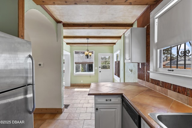 kitchen with visible vents, appliances with stainless steel finishes, tile counters, beamed ceiling, and pendant lighting