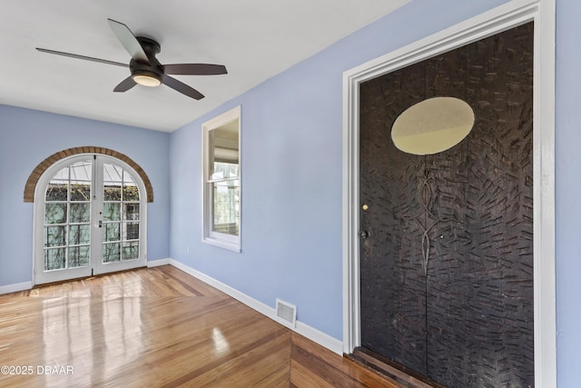 interior space with baseboards, visible vents, ceiling fan, wood finished floors, and french doors