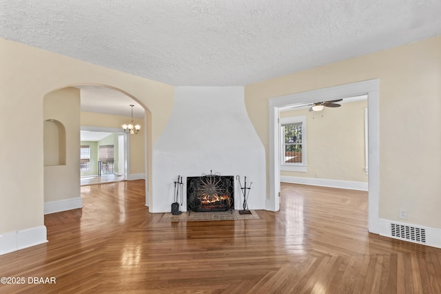 unfurnished living room with a large fireplace, visible vents, a textured ceiling, and baseboards