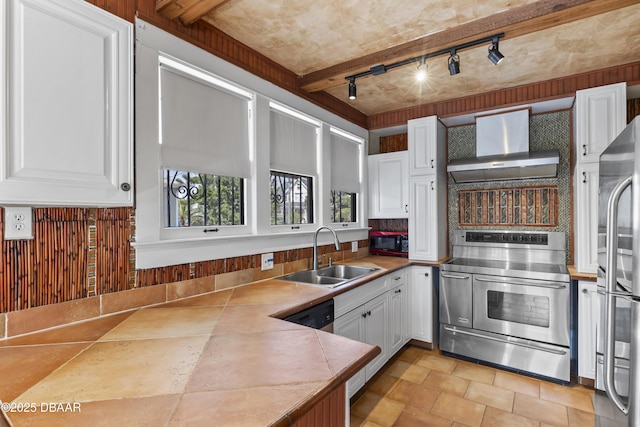 kitchen with wall chimney range hood, appliances with stainless steel finishes, white cabinets, and a sink
