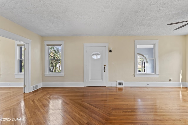 entryway featuring ceiling fan, a textured ceiling, visible vents, and baseboards