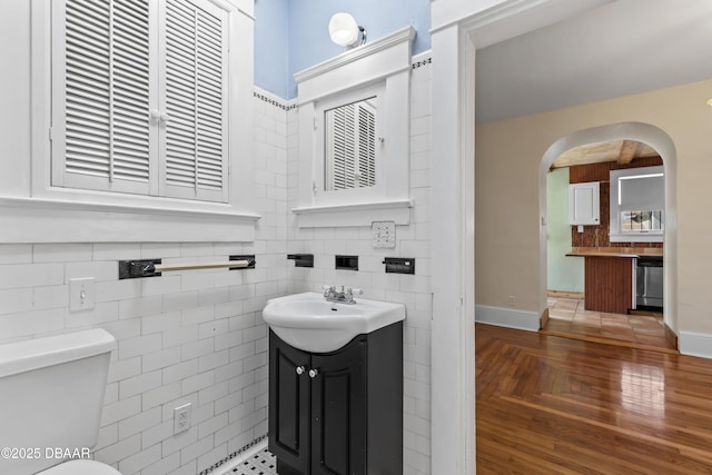 half bathroom featuring tile walls, vanity, and toilet
