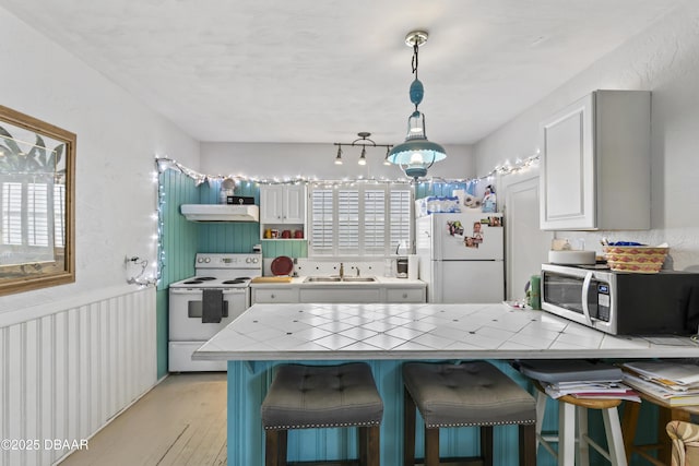 kitchen featuring white appliances, a sink, tile counters, and white cabinets