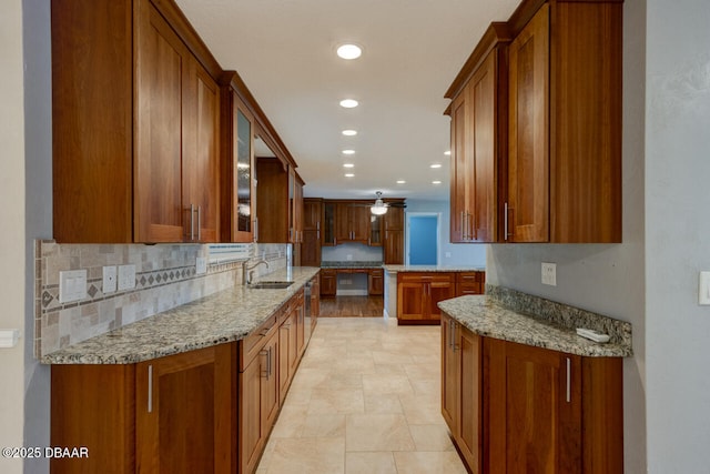 kitchen featuring light stone counters, ceiling fan, sink, and tasteful backsplash