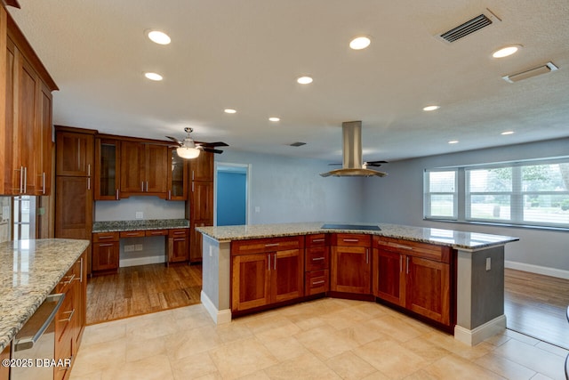 kitchen with built in desk, island exhaust hood, black electric stovetop, ceiling fan, and light stone countertops