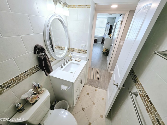 bathroom with vanity, toilet, tile patterned flooring, and tile walls