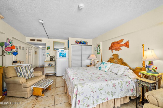 bedroom with a closet, light tile patterned flooring, and a textured ceiling