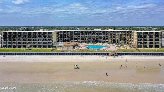 drone / aerial view of apartment complex / building, a nearby body of water, and a pool