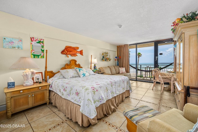 bedroom with light tile patterned flooring, access to exterior, a textured ceiling, a water view, and expansive windows