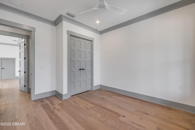 unfurnished bedroom with light wood finished floors, baseboards, visible vents, and a closet