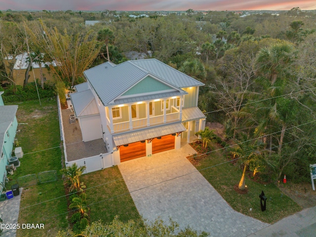 view of front facade featuring concrete driveway, a standing seam roof, a gate, metal roof, and a garage