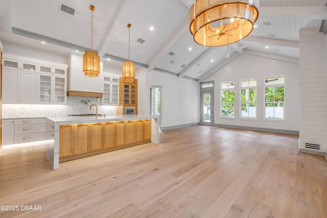 kitchen featuring visible vents, light wood-style floors, open floor plan, light countertops, and backsplash