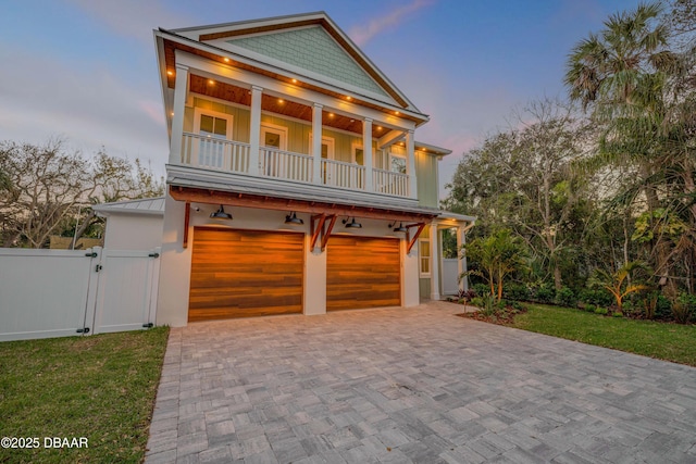 view of front facade with a balcony, an attached garage, a gate, decorative driveway, and board and batten siding