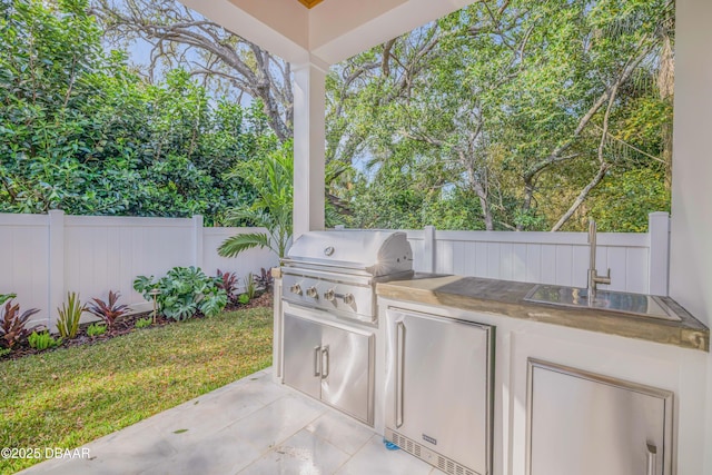 view of patio / terrace with an outdoor kitchen, a fenced backyard, grilling area, and a sink