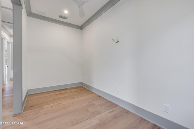 spare room featuring light wood-type flooring, visible vents, ceiling fan, and baseboards