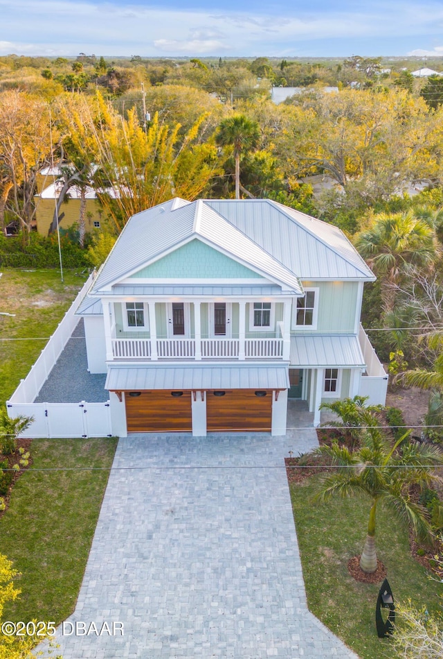 view of front of house featuring a standing seam roof, a gate, fence, decorative driveway, and a front yard