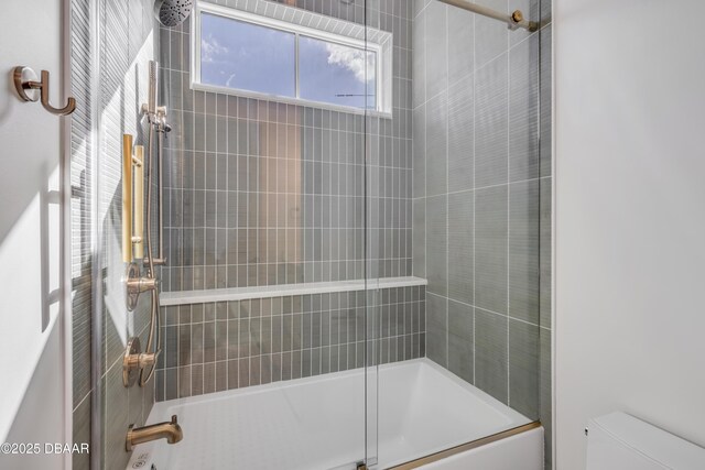 bathroom with toilet and combined bath / shower with glass door