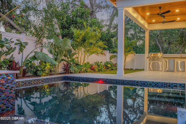 view of pool featuring an outdoor kitchen, a fenced backyard, a ceiling fan, grilling area, and a fenced in pool