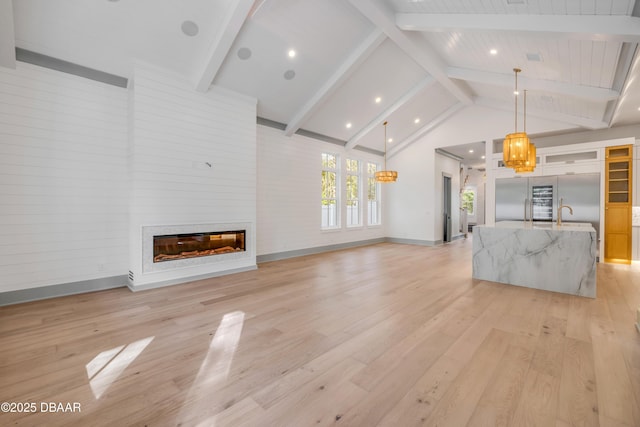 unfurnished living room with light wood-style floors, a fireplace, high vaulted ceiling, and beamed ceiling