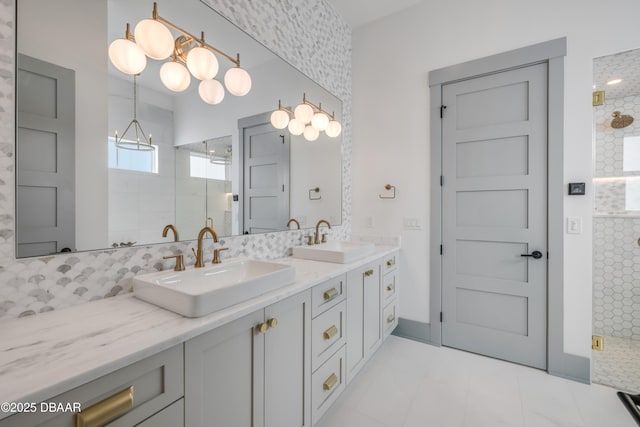 full bathroom with double vanity, a chandelier, a sink, and tiled shower