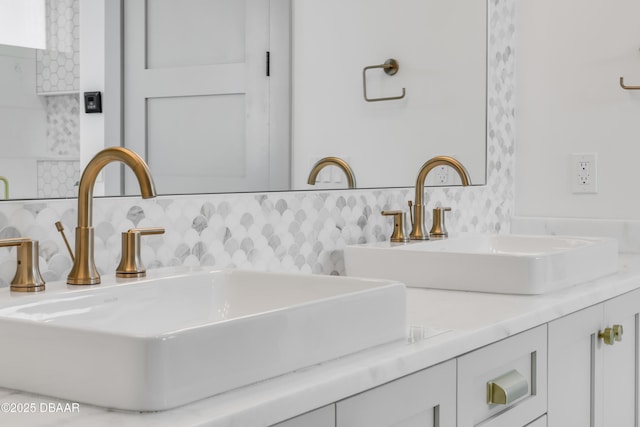 interior details featuring double vanity, backsplash, and a sink