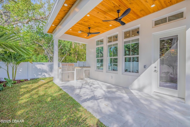 view of patio featuring fence, an outdoor kitchen, a ceiling fan, and area for grilling