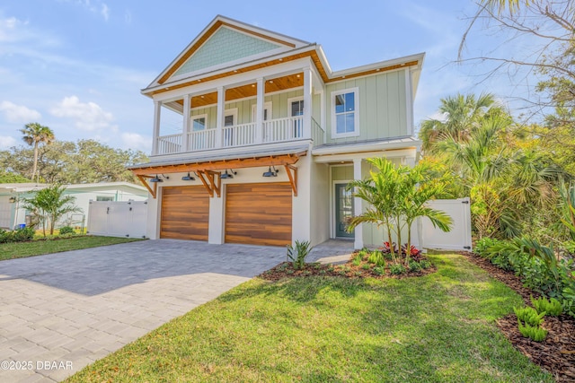 view of front of property featuring a balcony, an attached garage, fence, decorative driveway, and board and batten siding