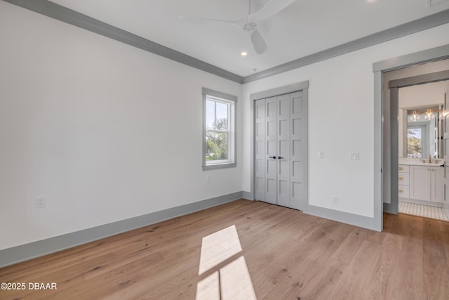 unfurnished bedroom featuring light wood-style floors, a closet, a sink, and baseboards