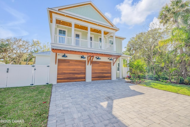 view of front of home featuring decorative driveway, board and batten siding, a front yard, and a gate