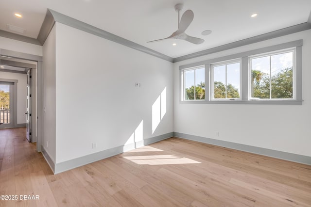 empty room with a healthy amount of sunlight, light wood-type flooring, ornamental molding, and baseboards