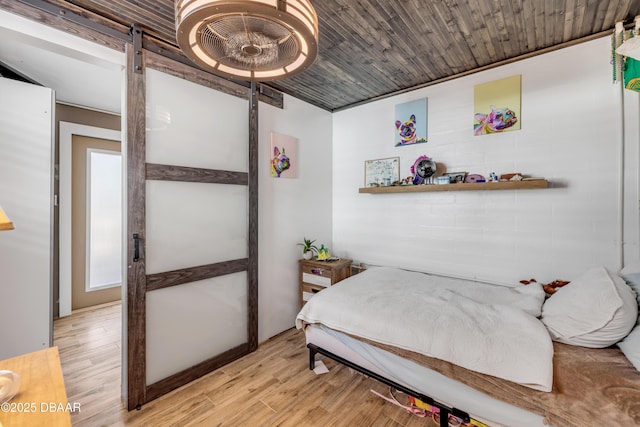 bedroom featuring light wood-style floors, wood ceiling, and a barn door