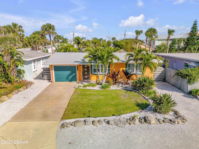 view of front facade with an attached garage, driveway, a front yard, and fence