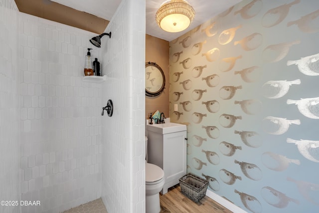 bathroom featuring toilet, a sink, a walk in shower, and wood finished floors