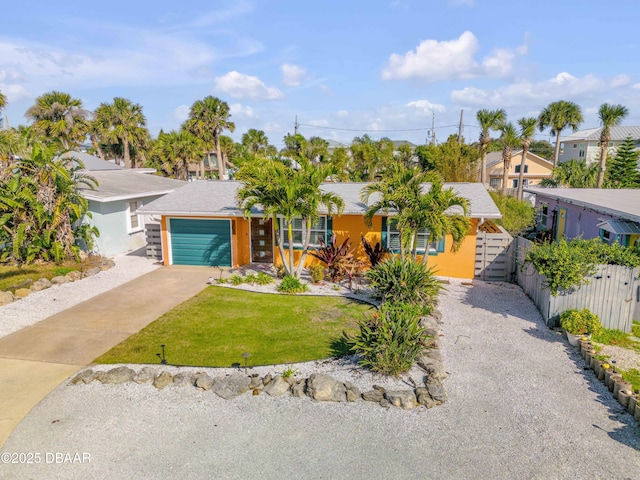 view of front of property featuring a garage, driveway, a residential view, fence, and a front lawn