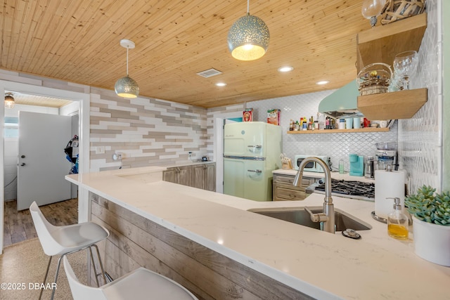 kitchen featuring open shelves, a peninsula, freestanding refrigerator, and pendant lighting