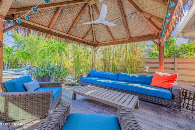 wooden terrace featuring ceiling fan, an outdoor living space, and a gazebo