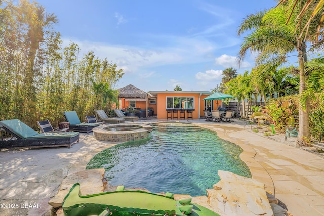 view of swimming pool featuring a fire pit, a patio area, fence, and a pool with connected hot tub