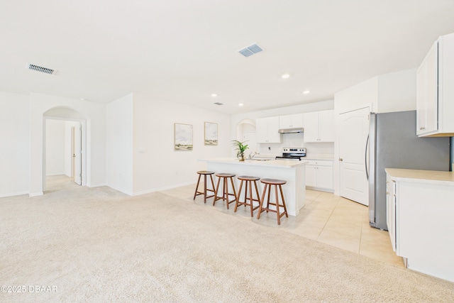 2625 Neverland Dr, New Smyrna Beach, FL 32168 - kitchen featuring light carpet, under cabinet range hood, visible vents, a kitchen bar, and stainless steel appliances